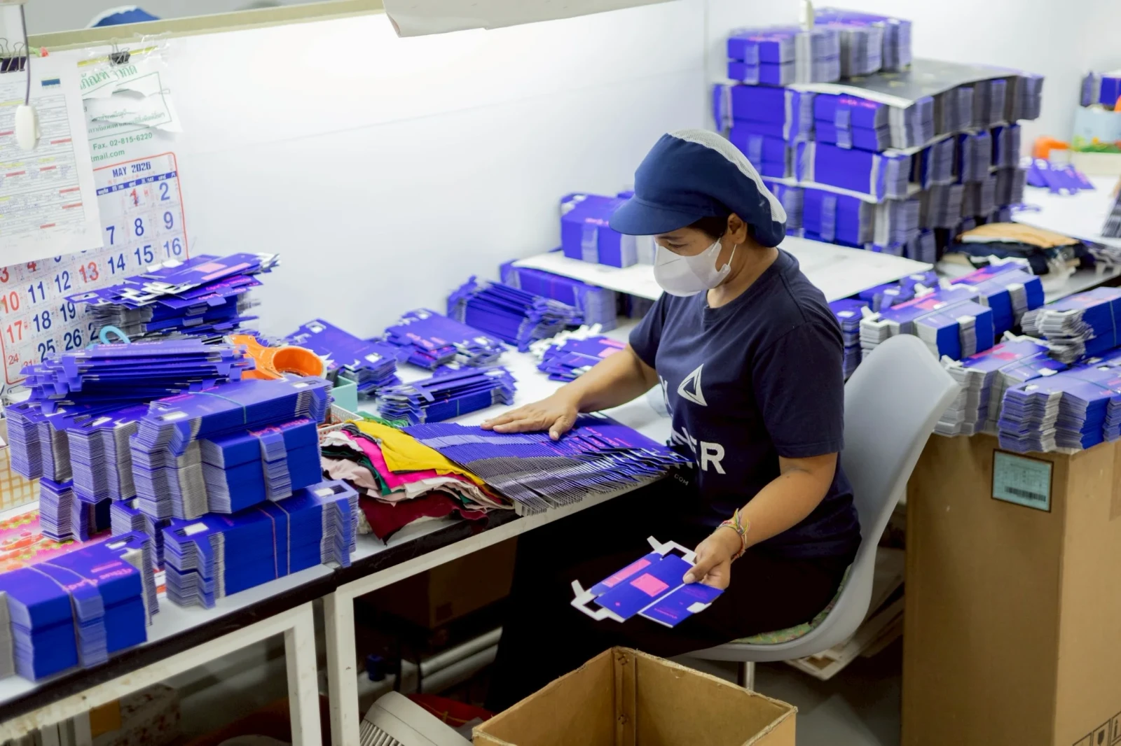 พนักงาน QC ตรวจสอบคุณภาพกล่องกระดาษอาร์ตการ์ดภายในโรงงานผลิตกล่อง